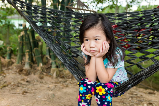 Unhappy girl sitting alone in hammock.. Outdoor on summer day.