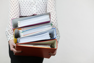 Woman holding heavy colorful binders with documents