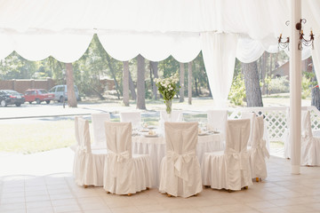 Beautiful white table and chairs in restaurant. Wedding party setting with white draperies
