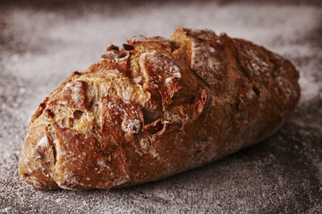 Walnut bread on flour and dark wood background.