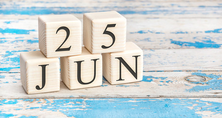 June 25th. Wooden cubes with date of 25 June on old blue wooden background.