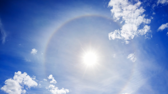 landscape from the blue sky with sun, white clouds and halo