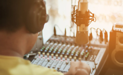 Professional condenser studio microphone over the abstract photo blurred of Hand adjusting audio...