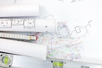 spirit level and zigzag ruler with rolls of construction blueprints on land-use project