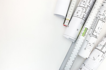 rolls of architectural blueprints, spirit level and zigzag ruler on white background