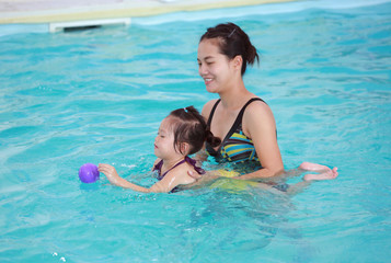 family of mother teaching kid in swimming pool.