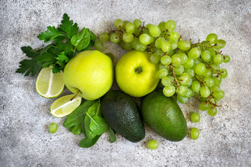 Selection of green vegetables and fruits on a gray concrete background. Detox, dieting, vegetarian, fitness, healthy lifestyle concept.