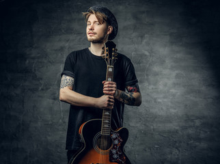 Studio portrait of stylish hipster male holds blues and jazz acoustic guitar.