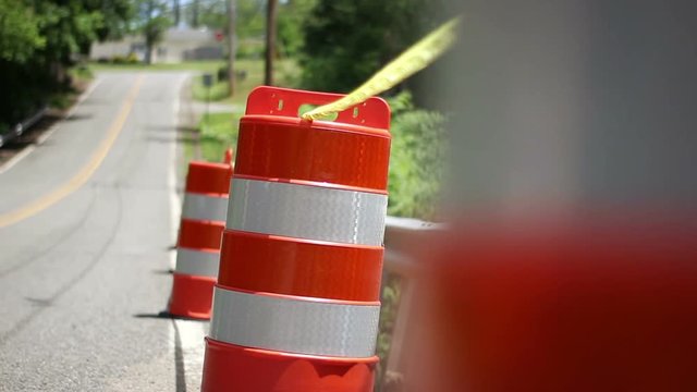 A row of construction barrels on the side of the road with yellow caution tape