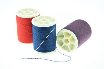 Spool of thread and needles on white background