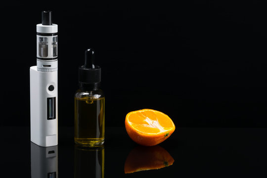 White electronic cigarette on a black background, next to the mandorin gum for filling