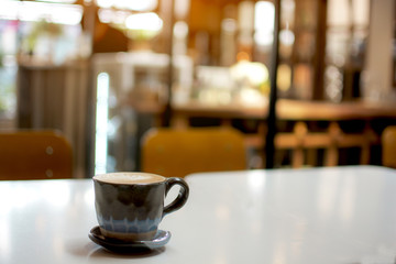 A cup of hot cappuccino on the table with coffee shop background