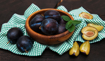 Bowl with  plums with green leaves