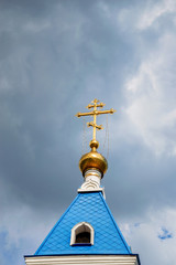 Orthodox cross at church rooftop against blue sky