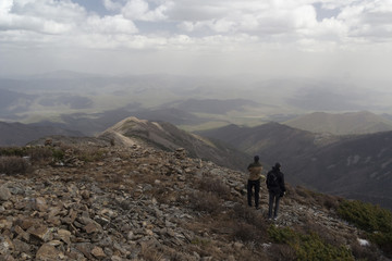 Two people stand side by side on top of the mountain and admire the mountain scenery
