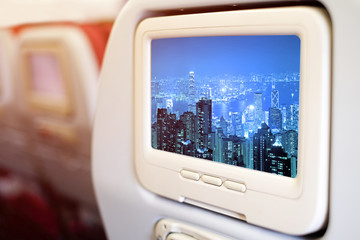 Aircraft monitor in front of passenger seat showing Panorama view Hong Kong cityscape at night.