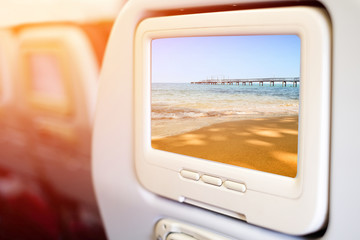 Aircraft monitor in front of passenger seat showing morning sunrise over the sea.