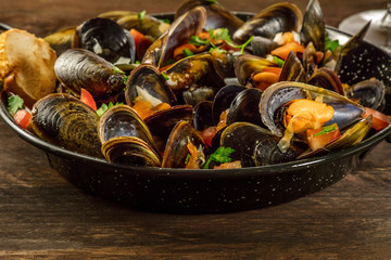 Skillet of marinara mussels on rustic background