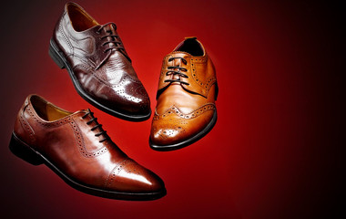 Fashion classical polished men's brown oxford brogues shades of brown oxford brogues.Conept flying shoes.Red background.Copy space