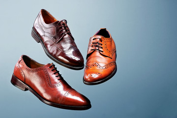 Fashion classical polished men's brown oxford brogues shades of brown oxford brogues.Conept flying shoes.Blue background.Copy space