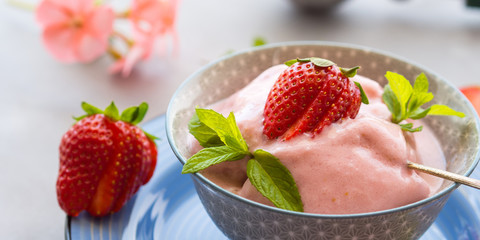 Home made strawberry ice cream in bowl with min leaves