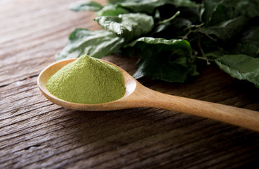 powder green tea and green tea leaves on wooden.