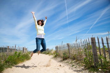 Miidle aged woman jumping on the beach
