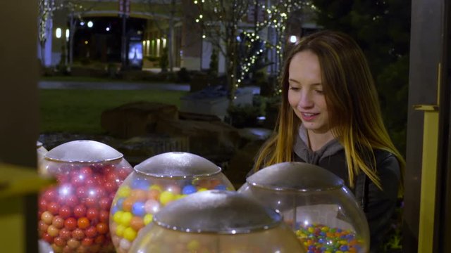 Teen Selects A Gumball From A Variety Of Machines, She Pops It In Her Mouth And Laughs At Someone Off-Screen