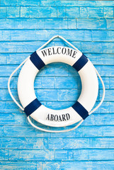 Life buoy with welcome on board on it hanging on blue wall