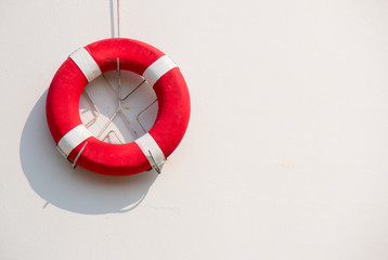 Red lifebuoy with white strip hanging on white wall  , had space on left side for creative