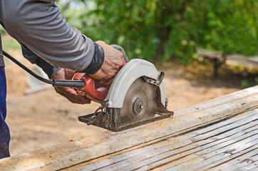 carpenter uses a circular saw to cut wood on the work area