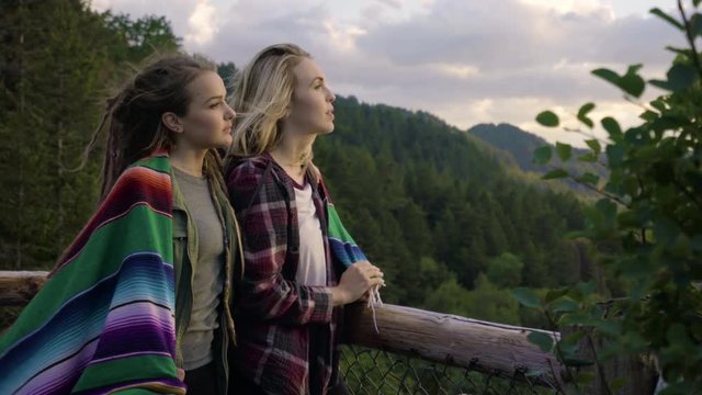 Young Women Watch The Sunset In The Mountains, Get Cozy In A Blanket And Chat