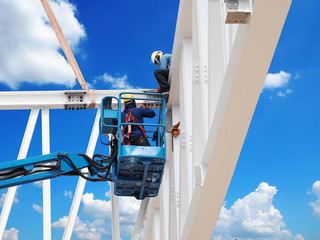 construction worker at construction site using lifting boom machinery