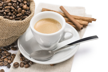cup of coffee on napkin with canvas bag full of coffee beans and cinnamon, on white background