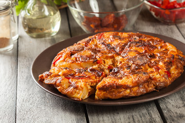 Tortilla de patatas. Spanish omelette with sausage chorizo, potatoes, paprika and egg, accompanied by olive oil
