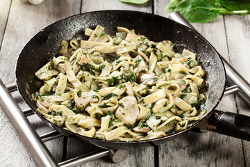 Tagliatelle pasta with spinach and mushrooms on a pan.