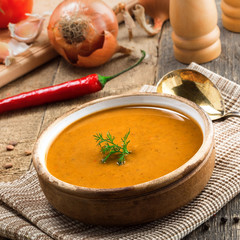 Soup made of lentil and vegetables in a rustic bowl on a canvas tablecloth. Delicious healthy vegetarian food on an old wooden table.