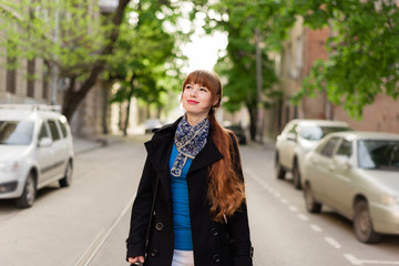 Beautiful young woman walking down the city street on a sunny day, examining the neighborhood.