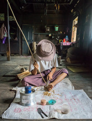 Basket Weaving. Old man is preparing willow branches to enforce bamboo baskets. Scene recorded in a traditional house at a remote Palaung village near Kyaukme, Shan State, Myanmar.