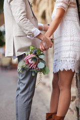 A guy holding a girl by the hand with a bouquet of flowers