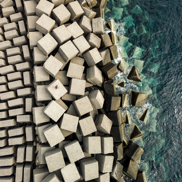 Aerial view of ocean wave crashing on geometric stone blocks