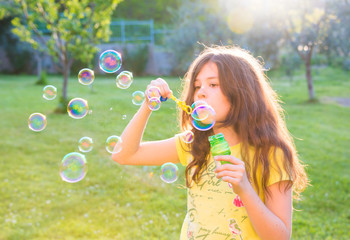 Girl blowing soap bubbles outdoors