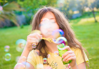Girl blowing soap bubbles outdoors