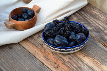 Blackberry and plum in plates on a wooden table
