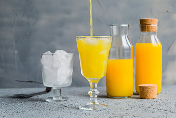 Fresh Orange Juice in Glass and Bottles and some Ripe Oranges on Grey Background. Healthy Drink, diet or Detox.