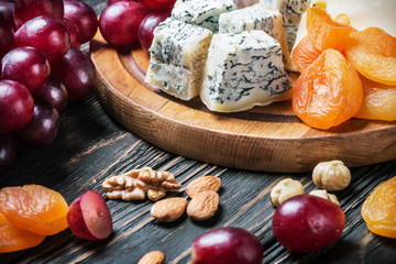Cheese plate with fruits and nuts on a wooden table