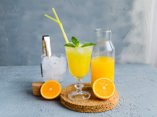 Fresh Orange Juice in Glass and Bottles and some Ripe Oranges on Grey Background. Healthy Drink, diet or Detox. © shutnica