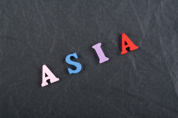 ASIA word on black board background composed from colorful abc alphabet block wooden letters, copy space for ad text. Learning english concept.