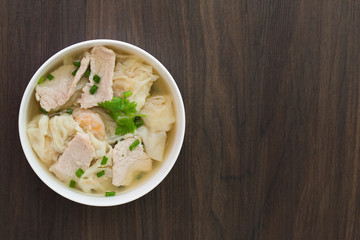 Shrimp wonton with braised pork in soup on wooden table / Select focus image and space for text..