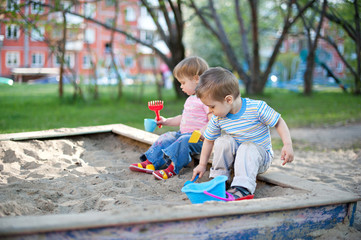 Two cute little children brother and sister playing in a sandbox